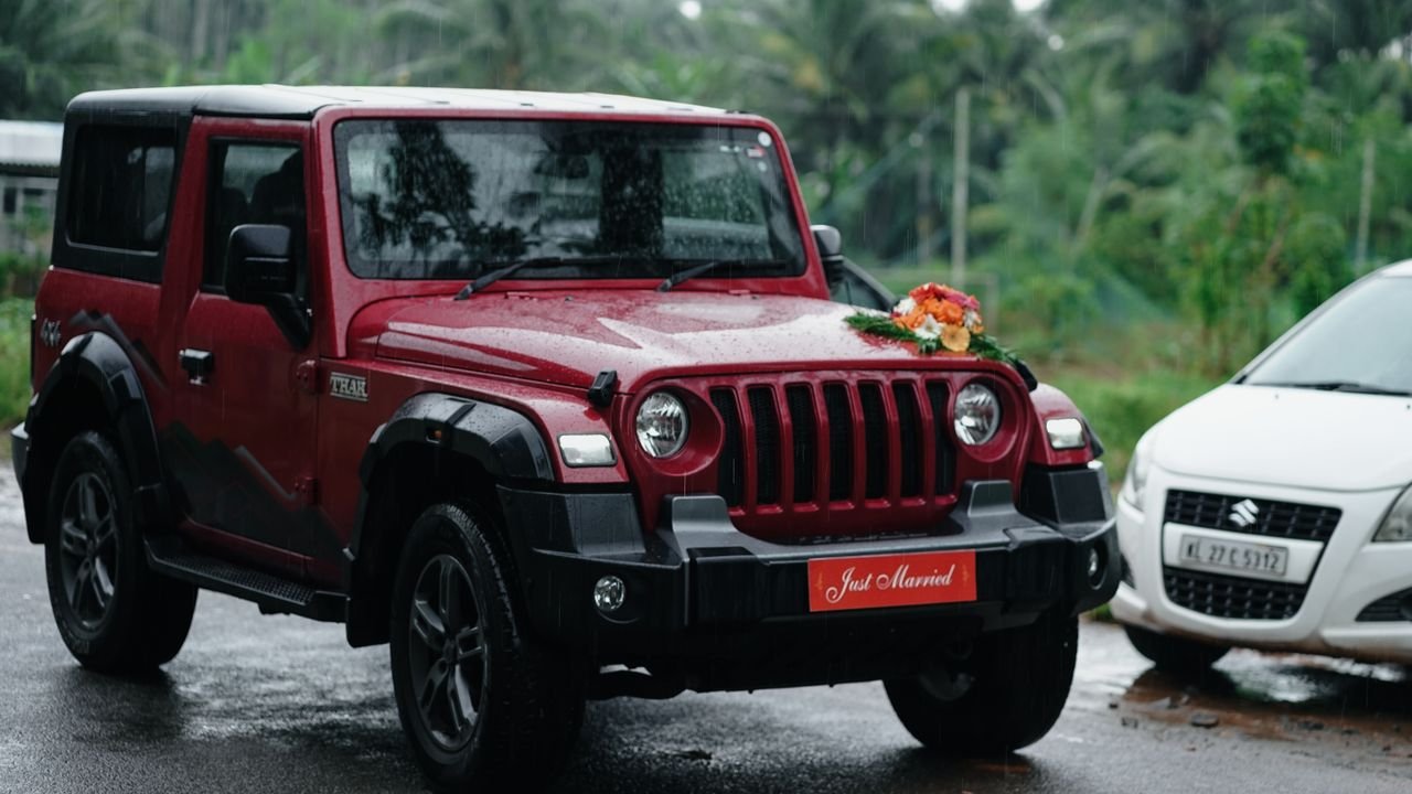 services-04 A red Jeep adorned with 'Just Married' sign in a tropical setting in Kozhikode, India.