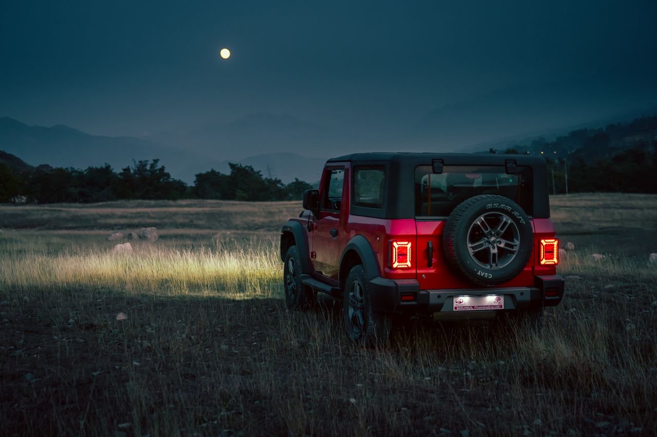 The Art of Drawing Readers In: Your attractive post title goes here A red Mahindra Thar SUV sits in a grassy field under the moonlight in rural India.